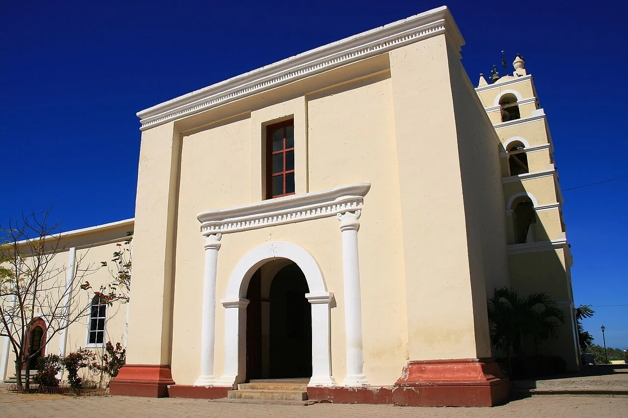 Fachada color crema y campanario de la Misión de Nuestra Señora del Pilar bajo cielo azul