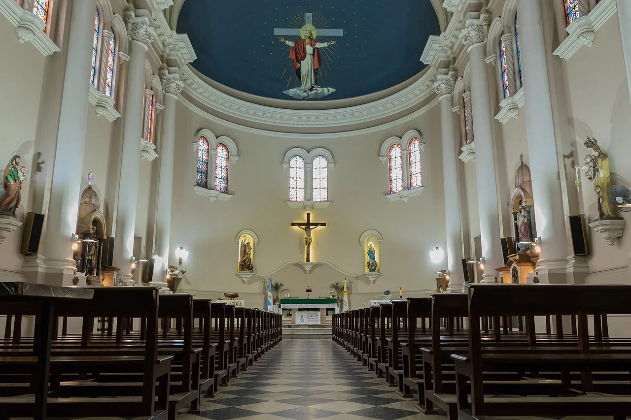 Interior de la Parroquia de San Miguel Arcángel, con bancas de madera, vitrales y una cúpula azul pintada