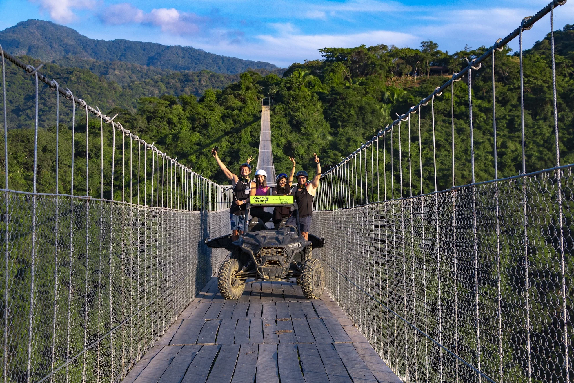 Viajeros en un vehículo todo terreno cruzando el puente colgante Jorullo sobre la selva de la sierra vallartense
