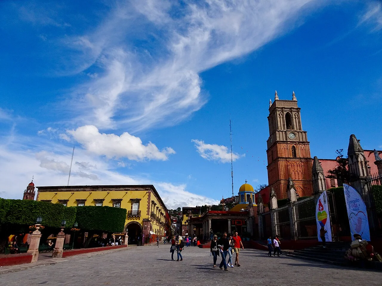 Plaza principal de San Miguel de Allende con paseantes, edificios coloniales y la torre de un templo