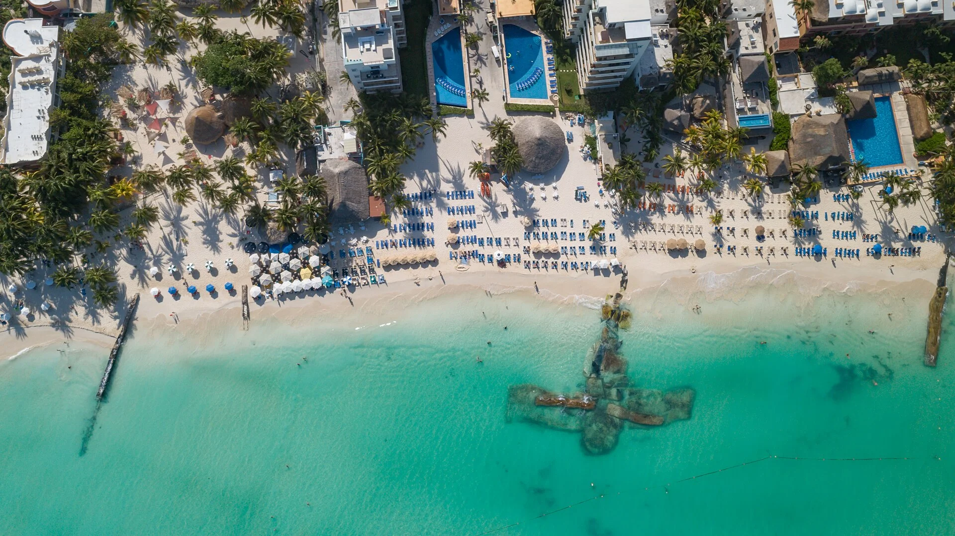 Vista cenital de una playa de Isla Mujeres con camastros, albercas y mar turquesa
