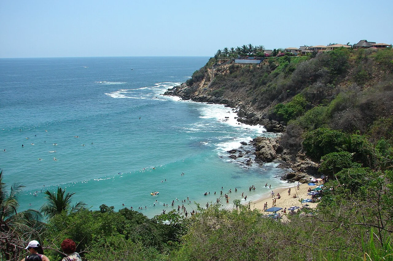Vista desde lo alto de Playa Carrizalillo, cala con bañistas rodeada de acantilados y vegetación