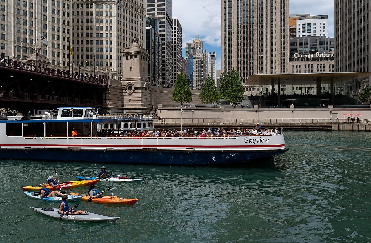 Barco turístico y kayaks navegando el río Chicago entre rascacielos del centro