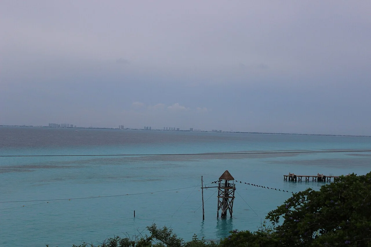 Vista del mar turquesa desde Garrafón, con una torre de tirolesa y la costa de Cancún al fondo
