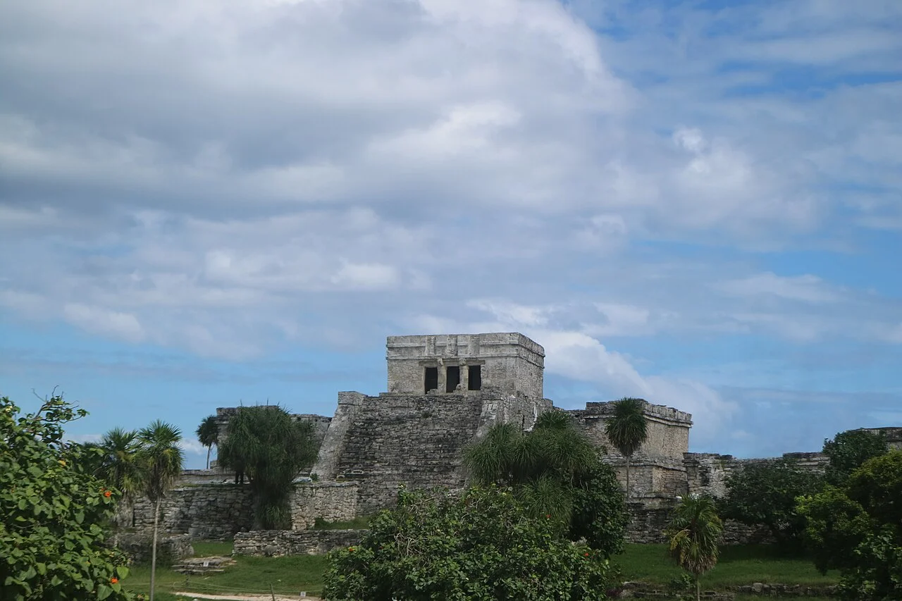 El Castillo de la zona arqueológica de Tulum rodeado de vegetación bajo un cielo nublado