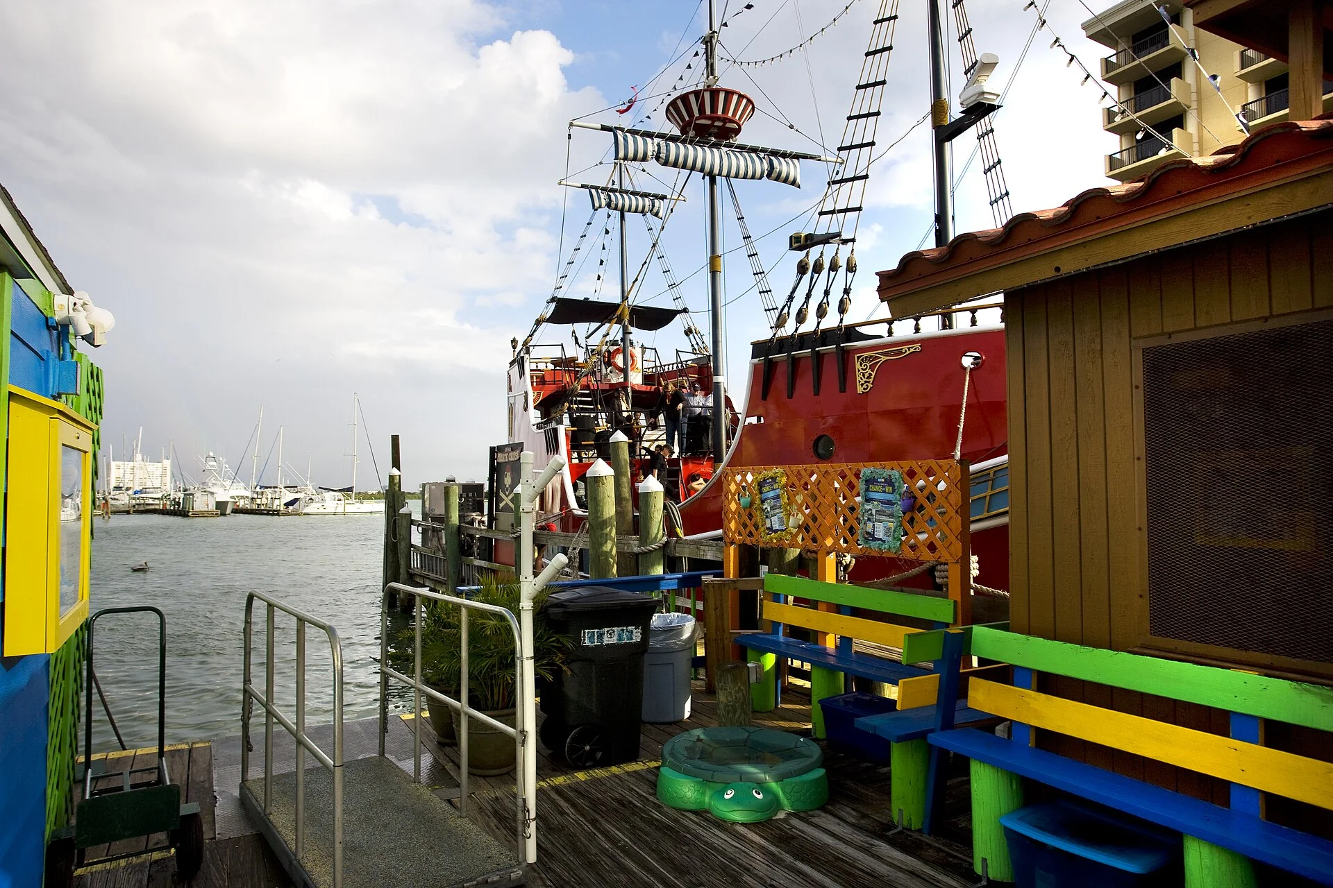 Barco pirata turístico atracado en la marina de Clearwater junto a un muelle de madera con bancas de colores