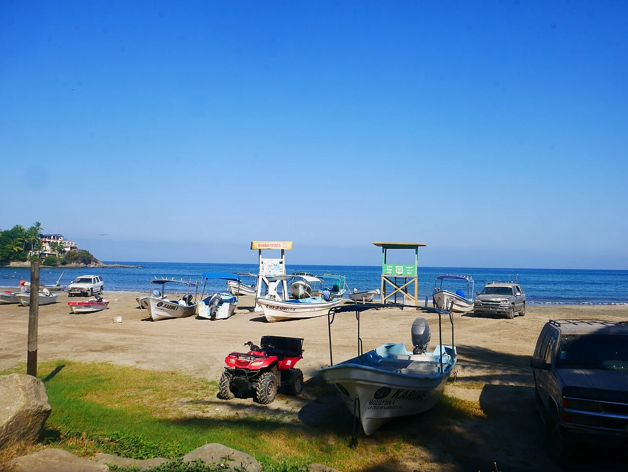 Playa Sayulita con lanchas en la arena, cuatrimoto y torres de salvavidas frente al mar