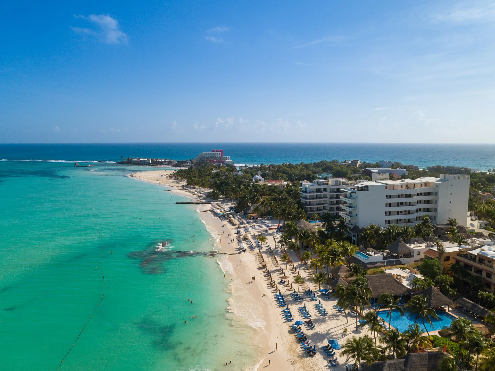Vista aérea de la costa norte de Isla Mujeres con hoteles, palmeras y playa de arena blanca