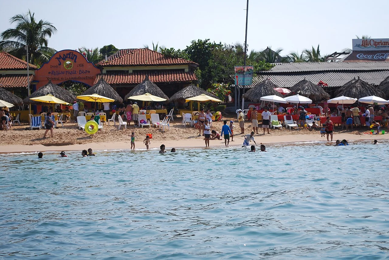 Playa de Isla Ixtapa con restaurantes, sombrillas de colores y bañistas en agua tranquila