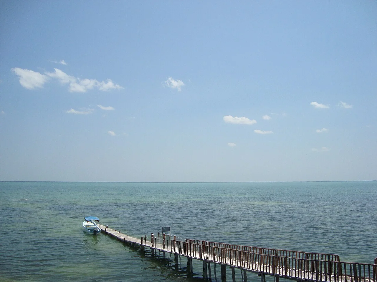 Muelle de madera con una lancha amarrada sobre las aguas tranquilas de la laguna en Isla Pájaros