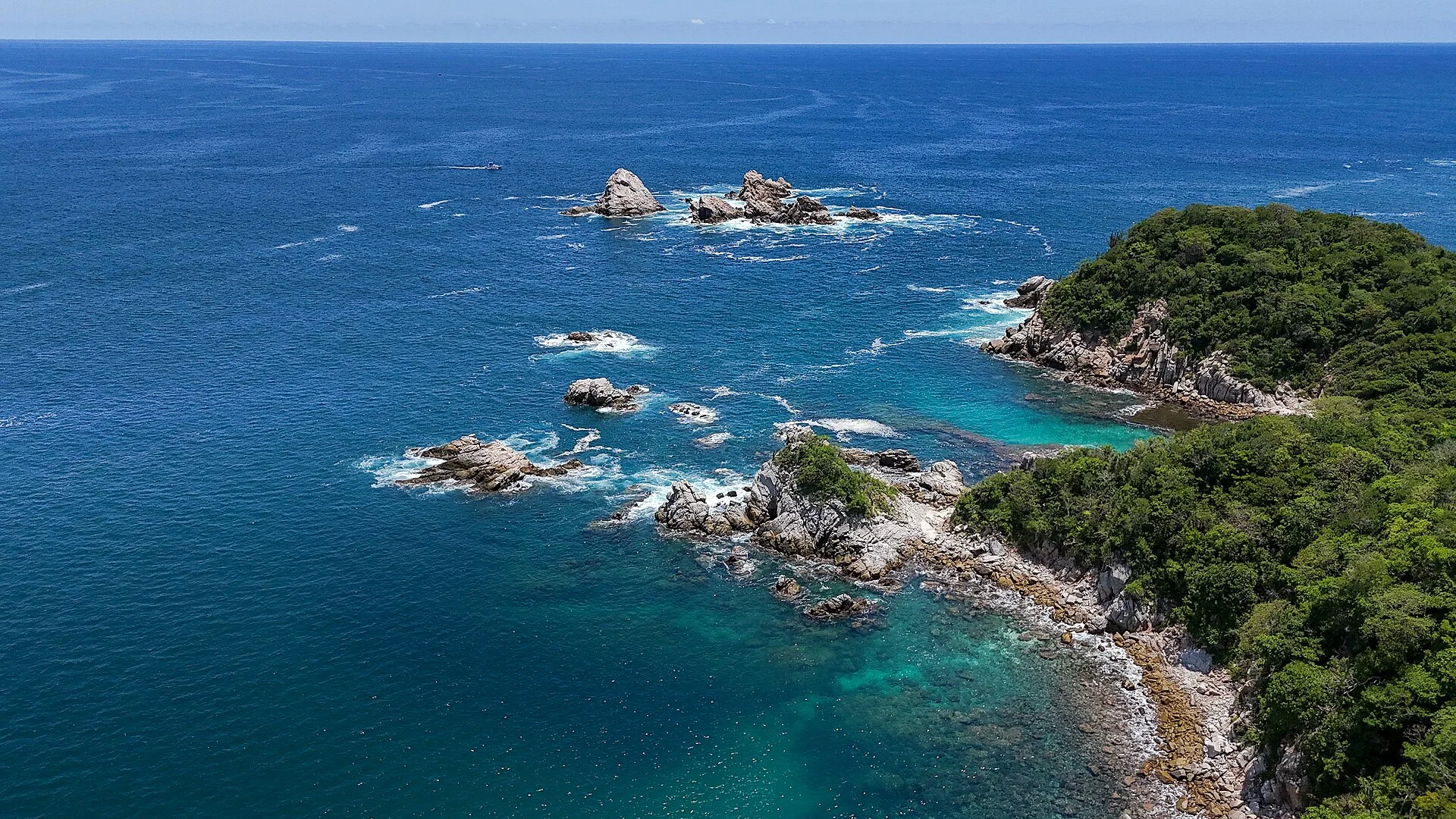 Costa rocosa de Huatulco vista desde el aire, con islotes, mar azul intenso y cerros cubiertos de vegetación