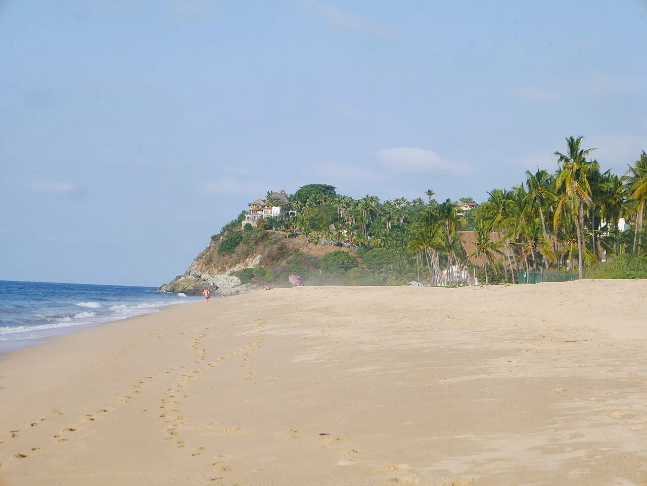 Playa amplia y casi vacía de San Pancho con palmeras y un cerro al fondo
