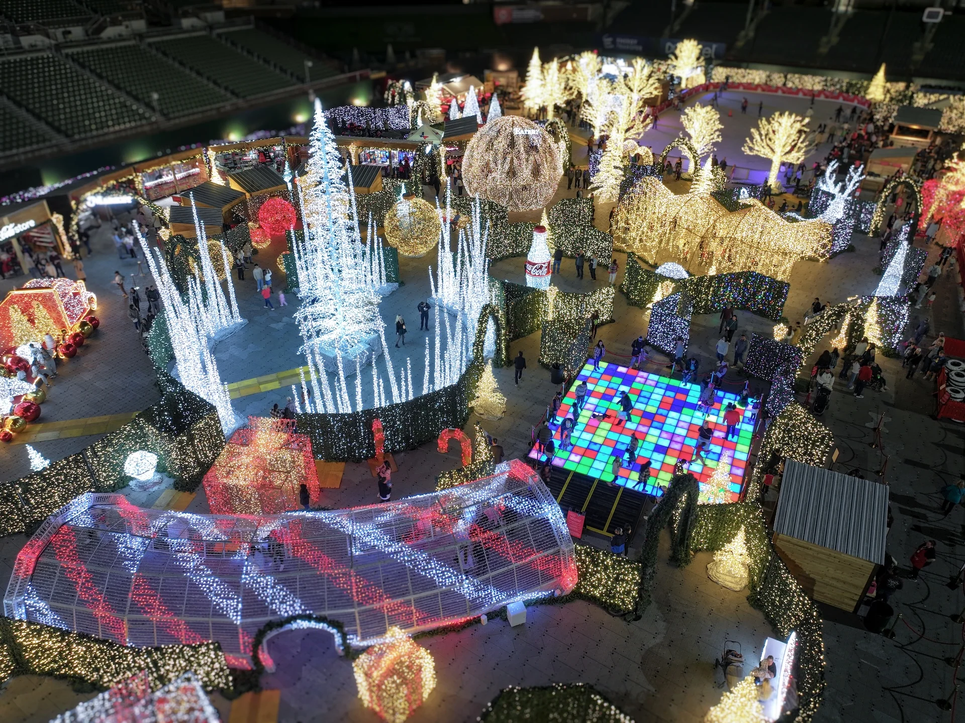 Vista aérea de un festival de luces navideñas con árboles iluminados, laberinto y atracciones