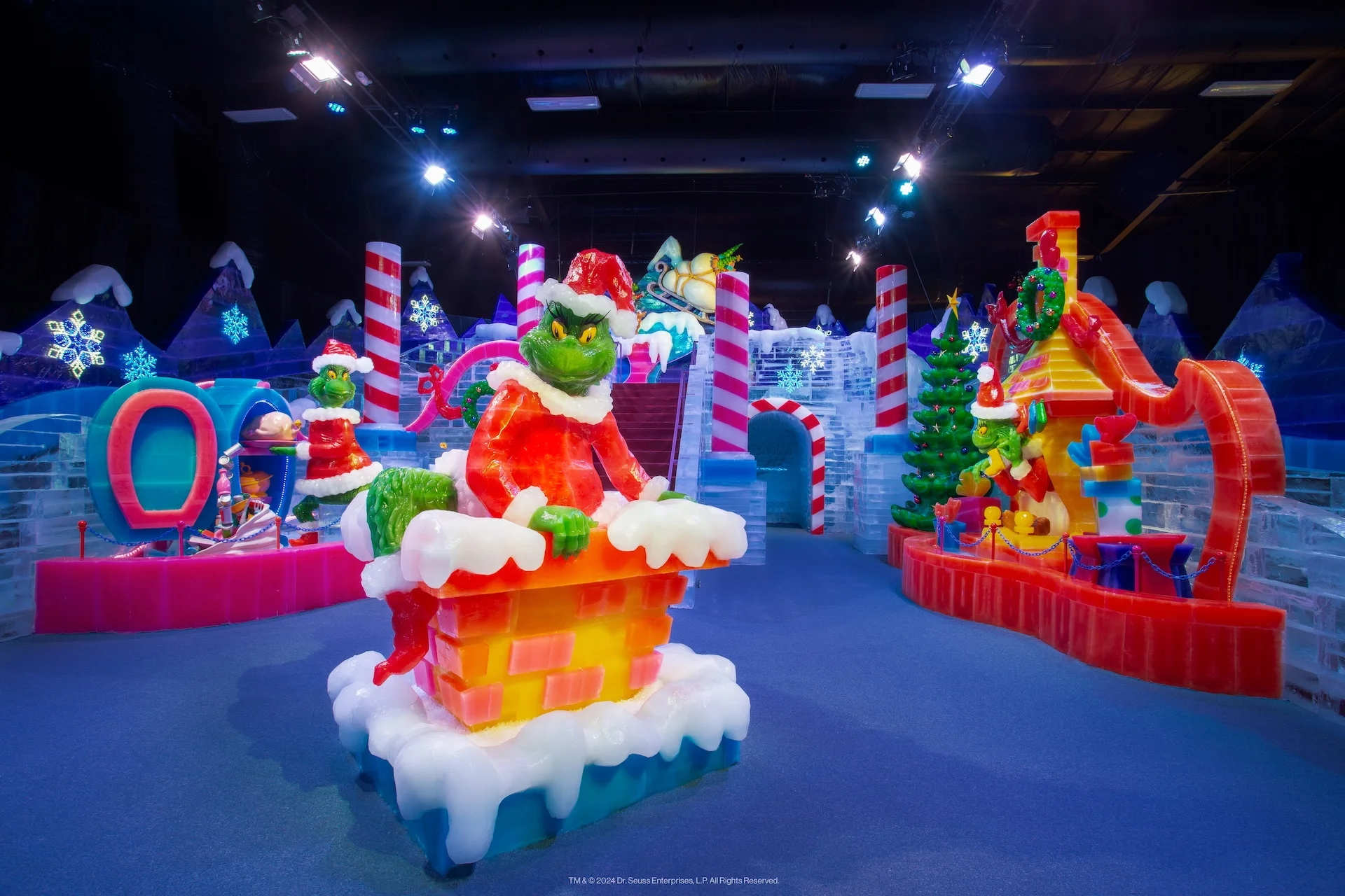Escultura de hielo del Grinch sentado en una chimenea, rodeado de figuras navideñas de colores